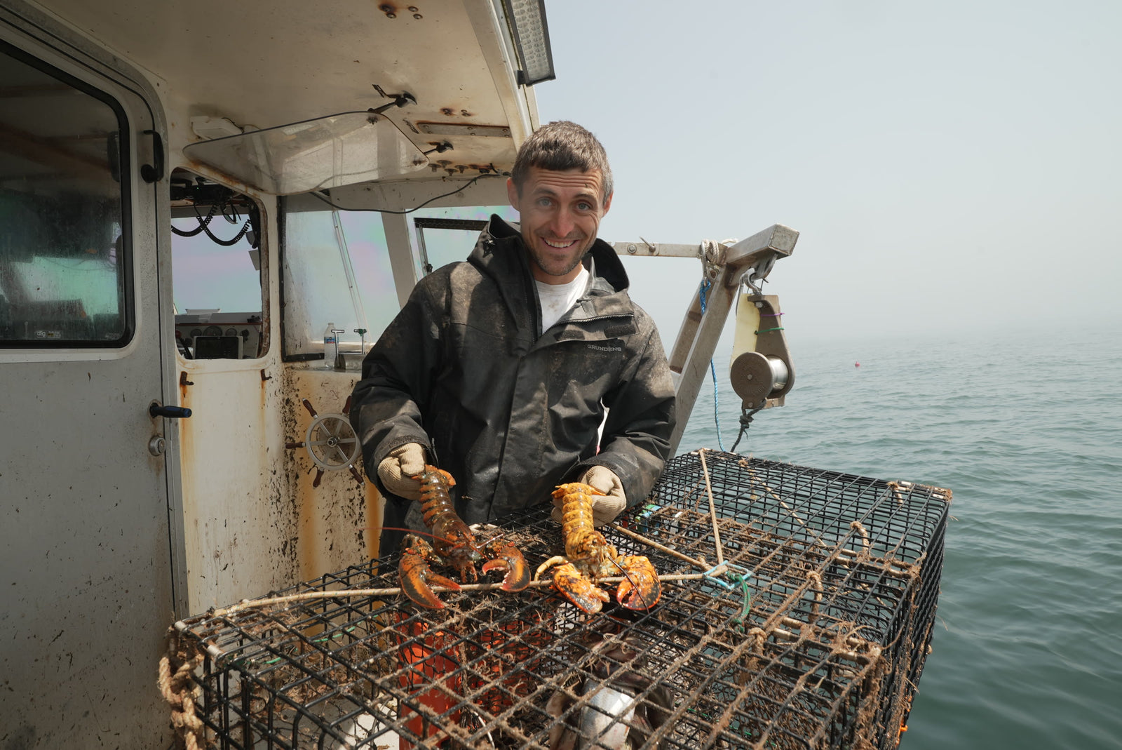 Jacob on deck in the fog with two calico lobsters