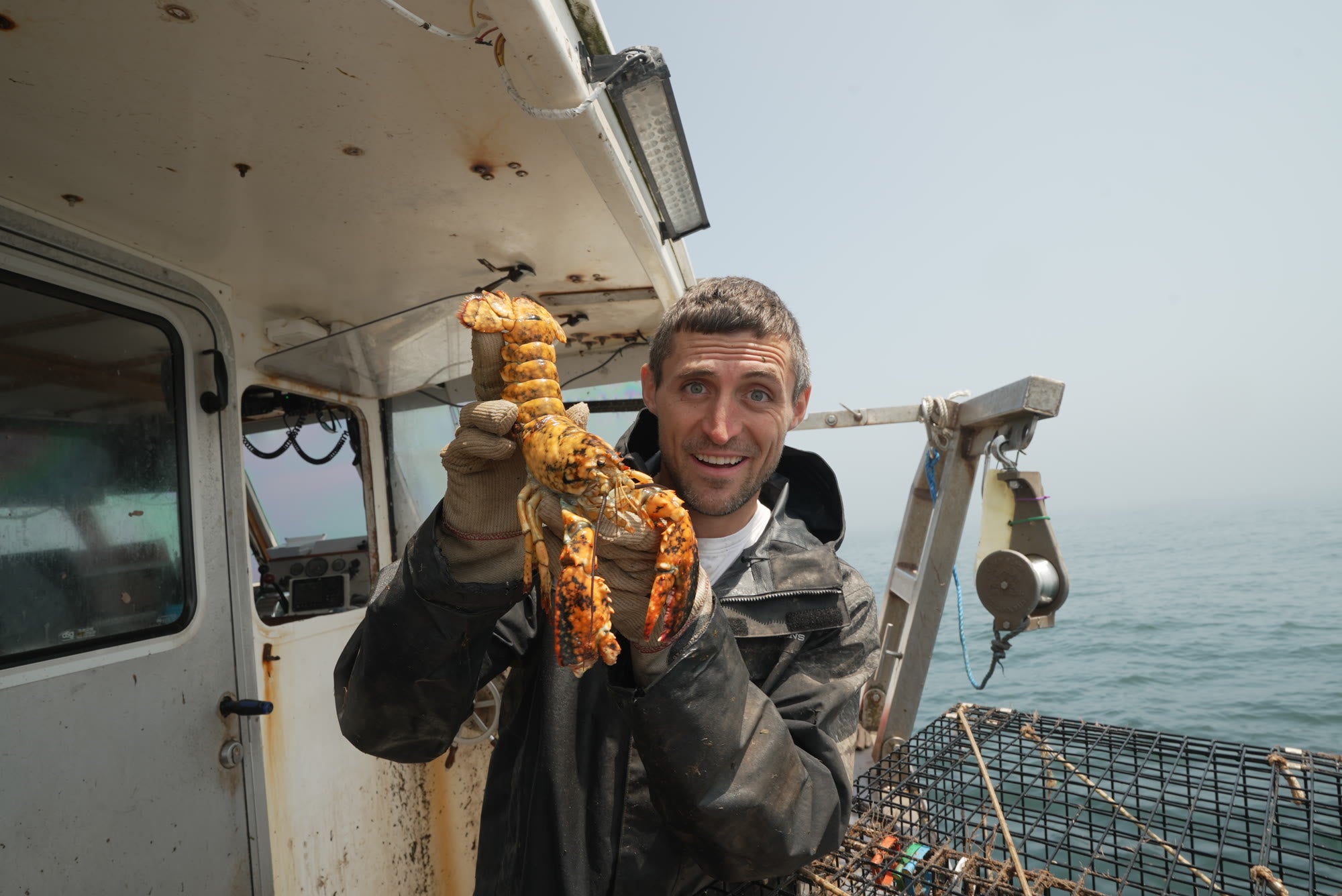 Jacob on deck holding a calico lobster on a foggy morning